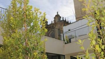 Un edificio moderno con una torre al fondo, rodeado de vegetación.