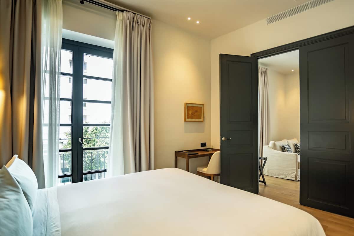 Una habitación de hotel con una cama grande, un escritorio y vistas al exterior.