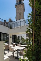 Un patio al aire libre con mesas y sillas, una torre de piedra y una bandera.