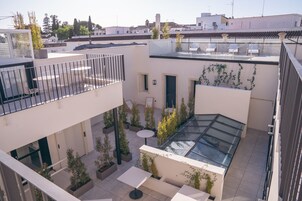 A multi-level courtyard with outdoor seating, potted plants, and a glass-roofed area.