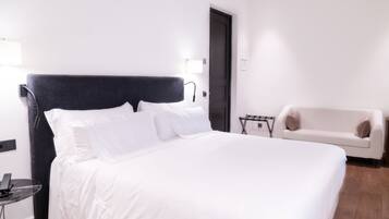 A modern hotel room with a large bed, a white sofa, and a small table.