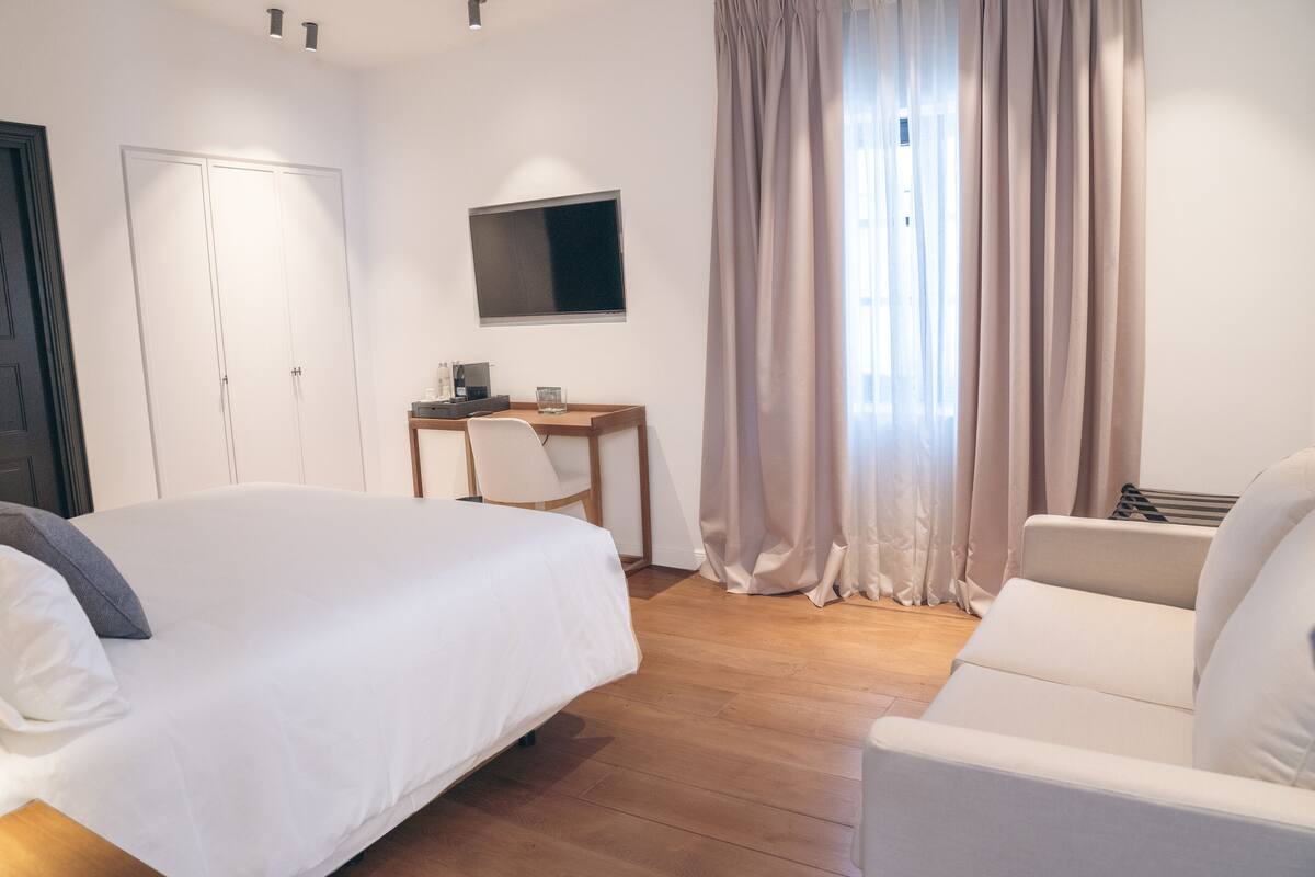Una habitación de hotel con una cama, un escritorio con computadora, una silla y un televisor.