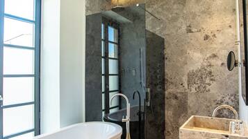 A modern bathroom with a freestanding bathtub, a walk-in shower, and two sinks.