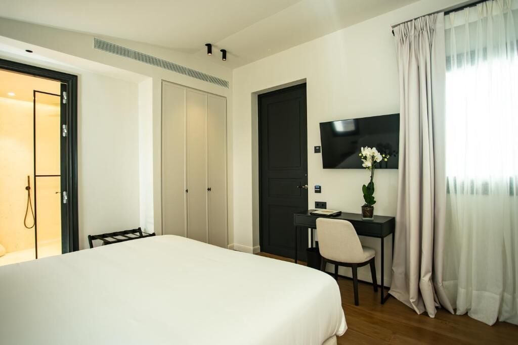 Habitación de hotel con una cama grande, un escritorio con silla, un televisor y una puerta que da a un baño.