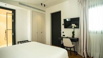 Habitación de hotel con una cama grande, un escritorio con silla, un televisor y una puerta que da a un baño.