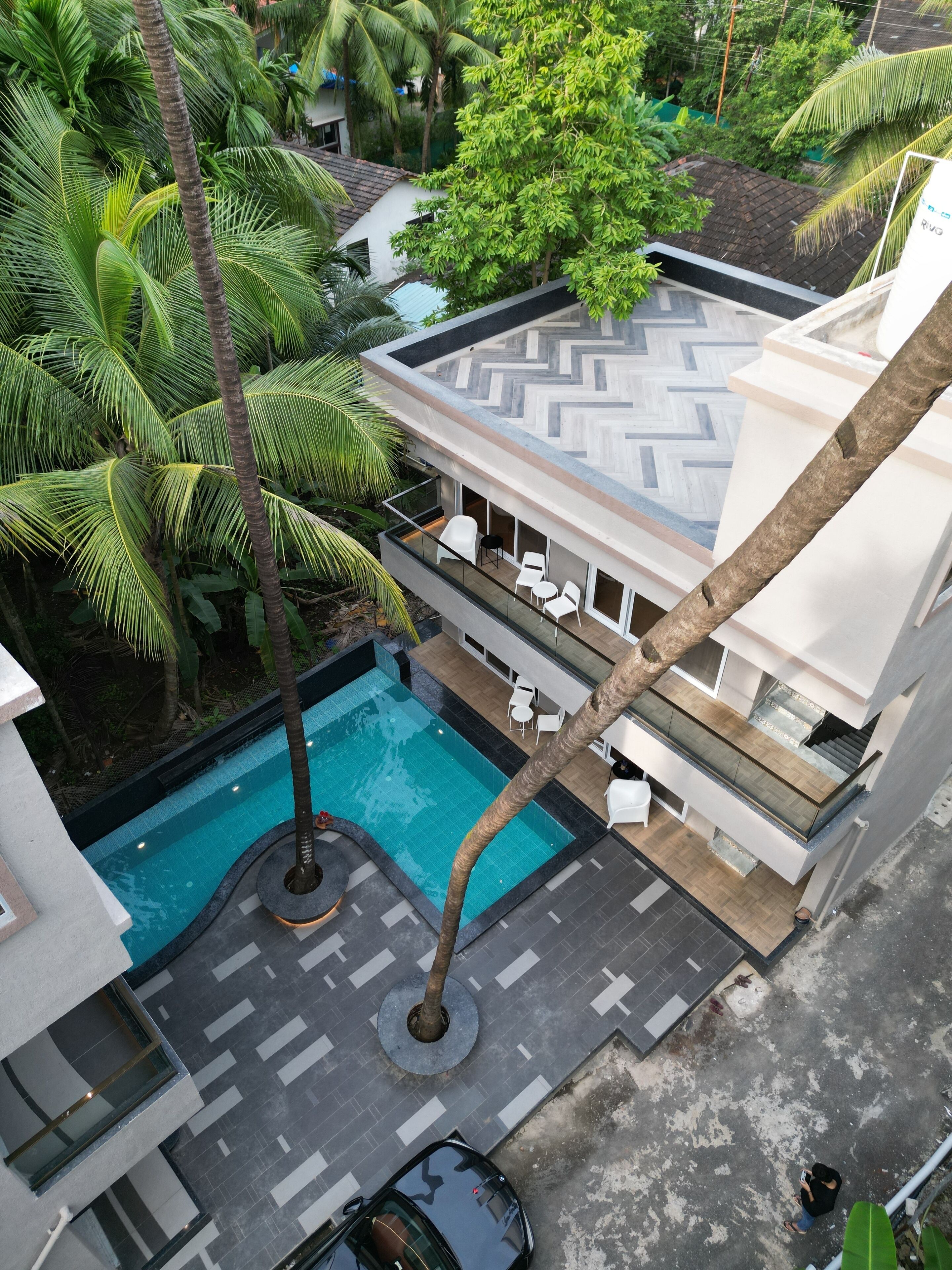 Un edificio moderno con piscina, mobiliario exterior y exuberante vegetación.
