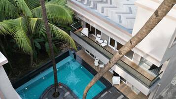 Un edificio moderno con piscina, mobiliario exterior y exuberante vegetación.