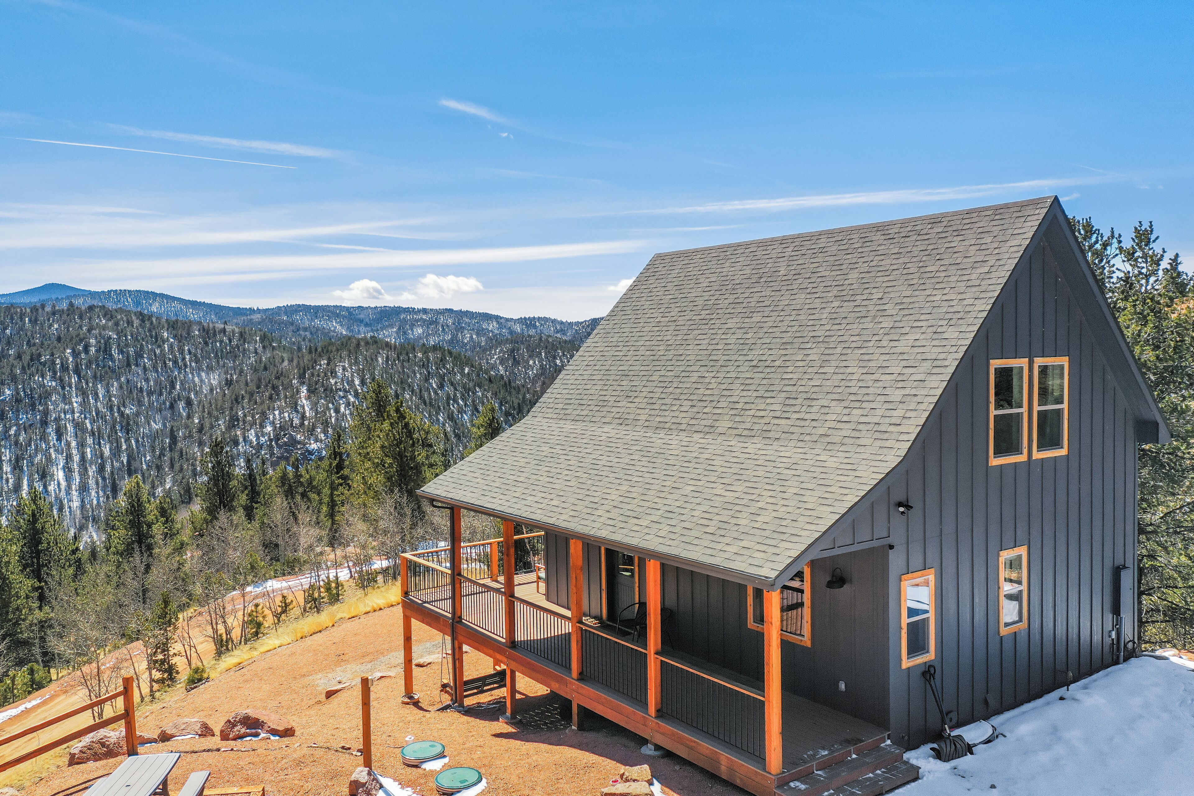 A cabin with a balcony, surrounded by a mountainous landscape.