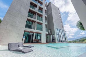 A modern hotel with a swimming pool, multiple balconies, and a view of the surrounding landscape. - Tropical Suite A602 at Viva Patong Condo (Patong)
