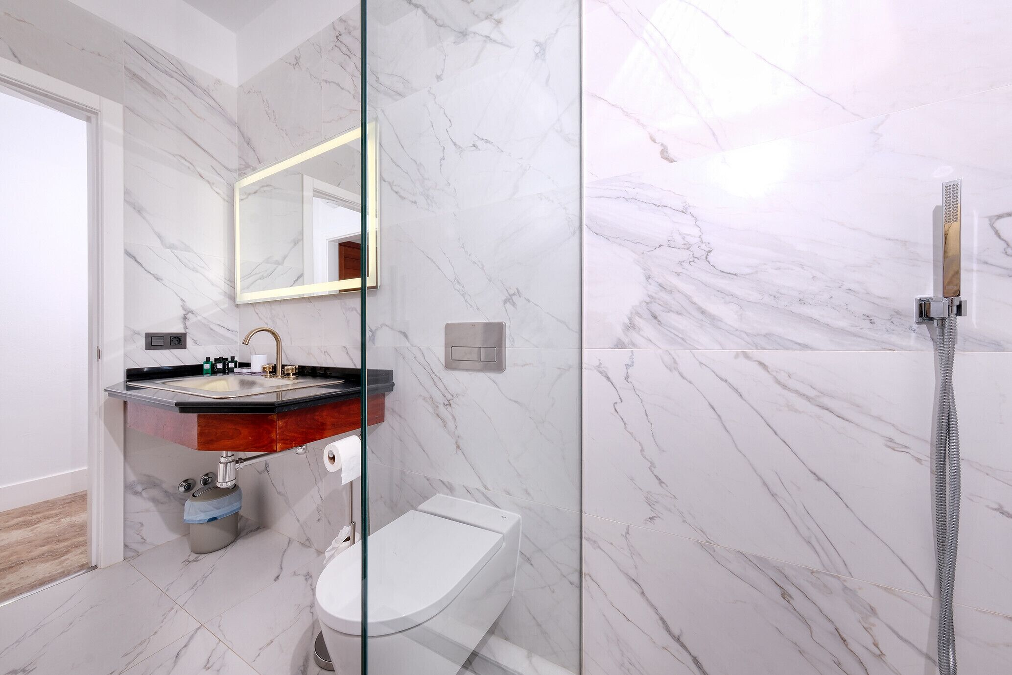 Une salle de bain moderne avec un sol en marbre, une douche en verre et un meuble-lavabo doté d’un évier et d’un miroir.