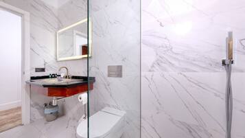 Une salle de bain moderne avec un sol en marbre, une douche en verre et un meuble-lavabo doté d’un évier et d’un miroir.