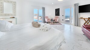 A hotel room with a large bed, a TV, a seating area with two chairs, and a view of the ocean. - Casa Serena 10, Suite  5 • Breakfast included (+18) (Macher)