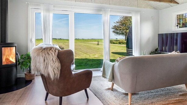A modern living room with a large window, a fireplace, and a sofa. - "Kanerva" - 100m to the fjord by Interhome (Storvorde)