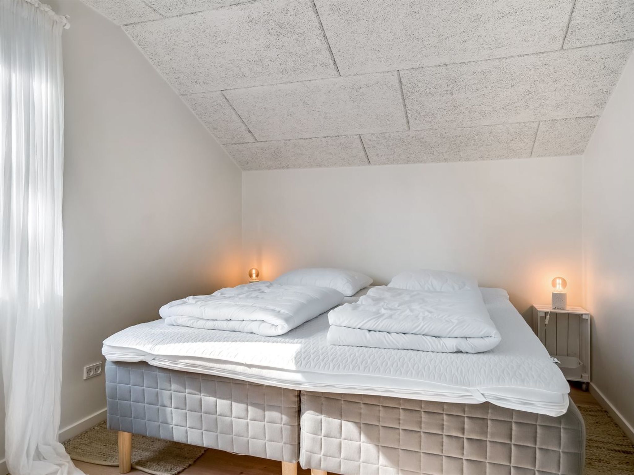 Un dormitorio con una cama, dos lámparas de noche y una luz en el techo.