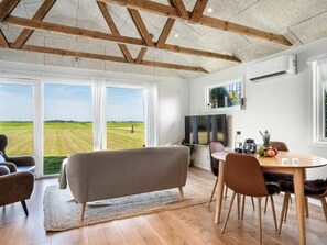 Un salon moderne avec une grande fenêtre, un canapé, une table à manger et un téléviseur.