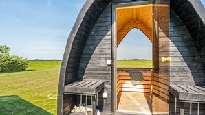 A wooden cabin with a large arch entrance, a wooden deck, and a bench. - "Kanerva" - 100m to the fjord by Interhome (Storvorde)
