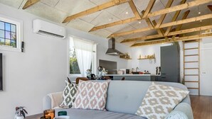 A modern living room with a light grey sofa, patterned cushions, a wooden coffee table with books and candles, and a kitchen in the background. - "Kanerva" - 100m to the fjord by Interhome (Storvorde)