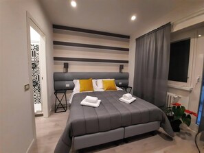 A modern bedroom with a large bed, grey bedding, a grey headboard, and a window with curtains. - MARITZA GUEST HOUSE 1 (Rome)