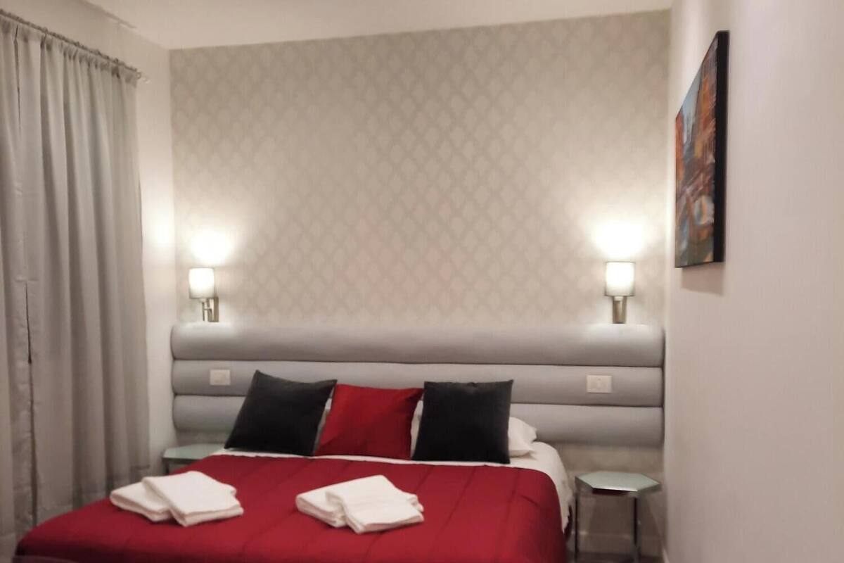 Ein modernes Hotelzimmer mit einem großen Bett, zwei Nachttischen und einem kleinen Seitentisch.