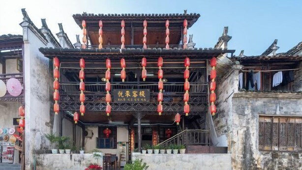 A traditional building with a two-story structure, a covered entrance, and red lanterns hanging above. - Likeng Yuelai Inn (Wuyuan)