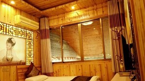 A wooden room with two beds, a window, and a wall-mounted air conditioner. - Likeng Yuelai Inn (Wuyuan)