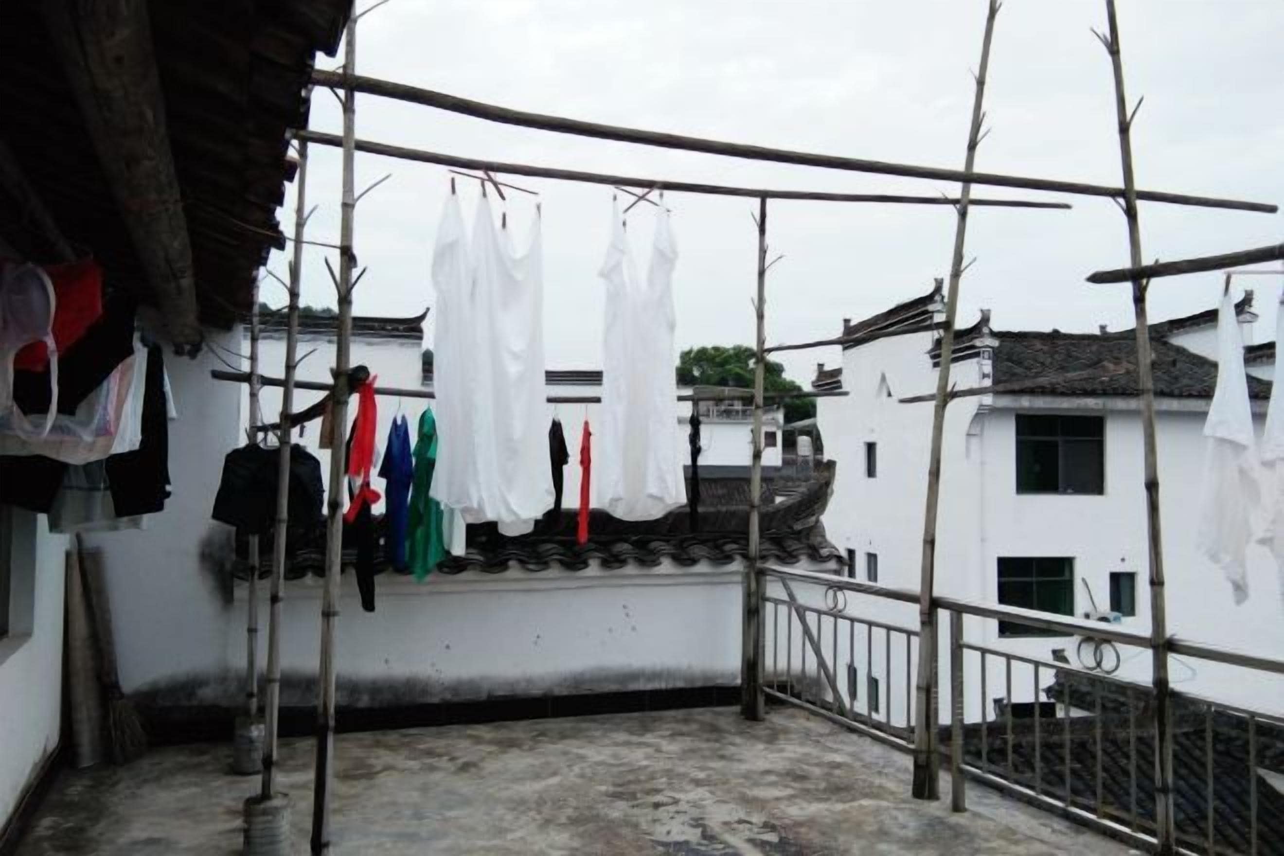 A rooftop with clothes hanging on a line, a ladder, and a railing.