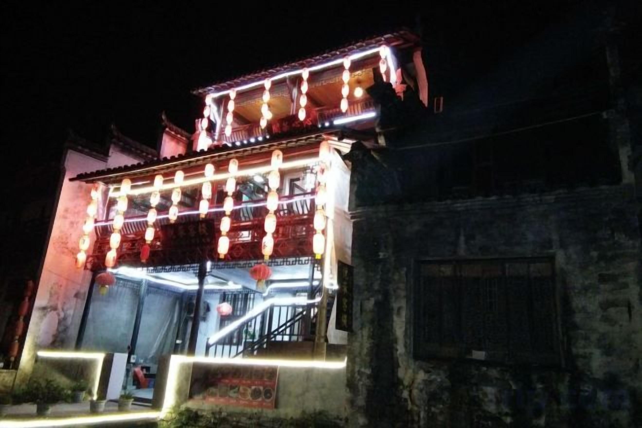 A traditional building with a balcony and illuminated string lights.