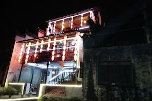 Un bâtiment traditionnel doté d’un balcon et illuminé par des guirlandes lumineuses.