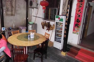 Uma mesa redonda com cadeiras, uma geladeira e uma parede com decoração pendente.