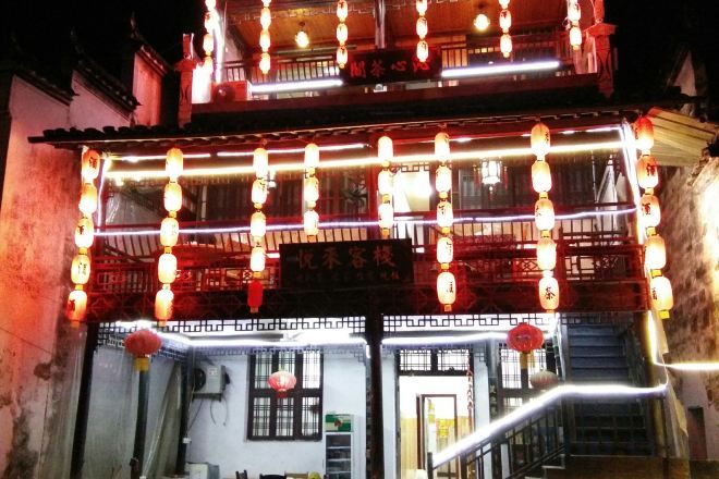 A traditional building with a balcony, illuminated by string lights and lanterns.