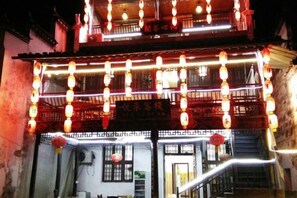 A traditional building with a balcony, illuminated by string lights and lanterns. - Likeng Yuelai Inn (Wuyuan)
