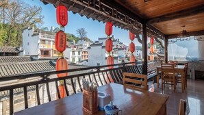 A traditional wooden dining area with a view of traditional buildings. - Likeng Yuelai Inn (Wuyuan)