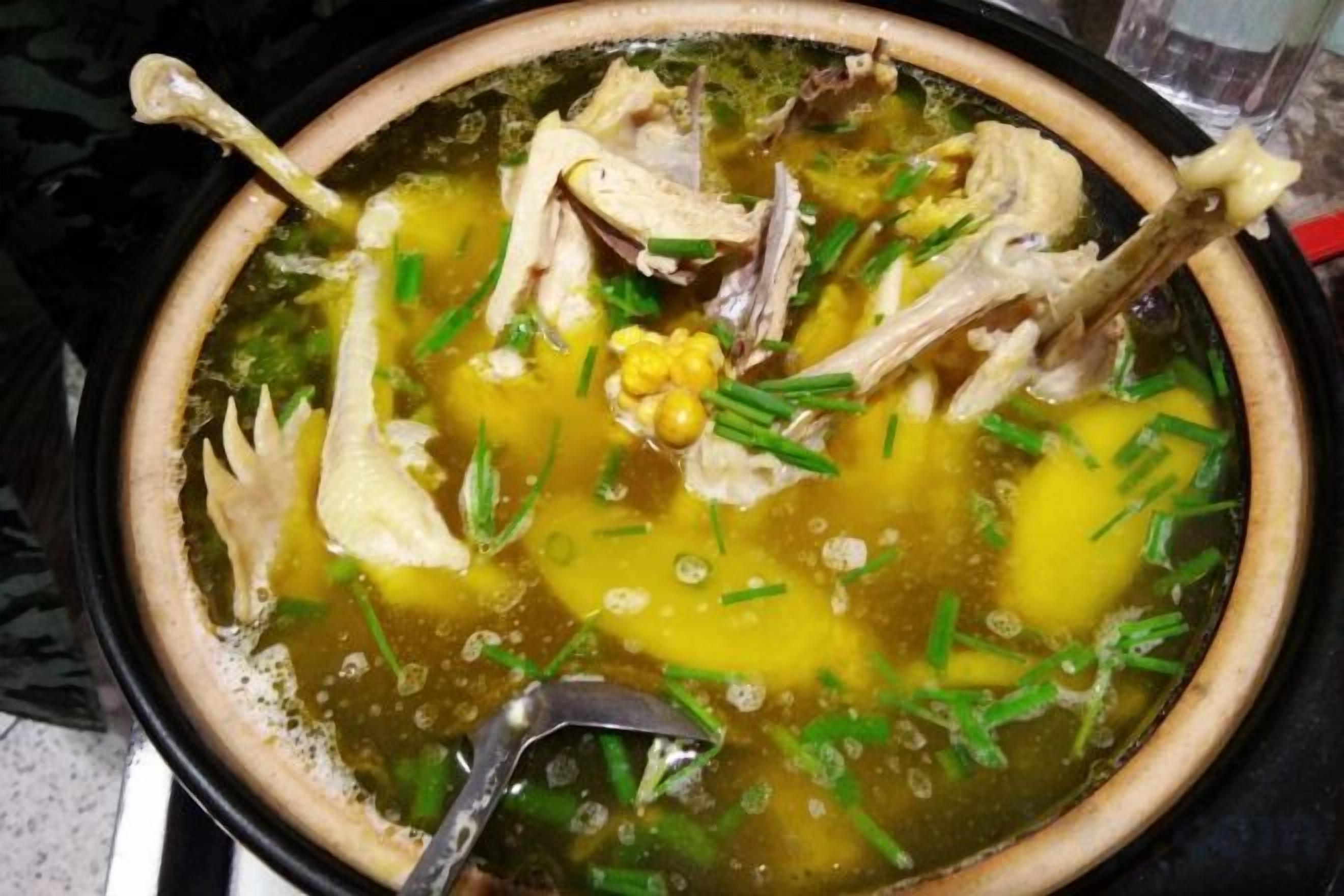 Un tazón de sopa con carne y maíz sobre la estufa.