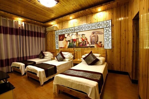 Quarto de hotel com paredes de madeira, duas camas com roupa de cama branca e um painel decorativo grande acima das camas.
