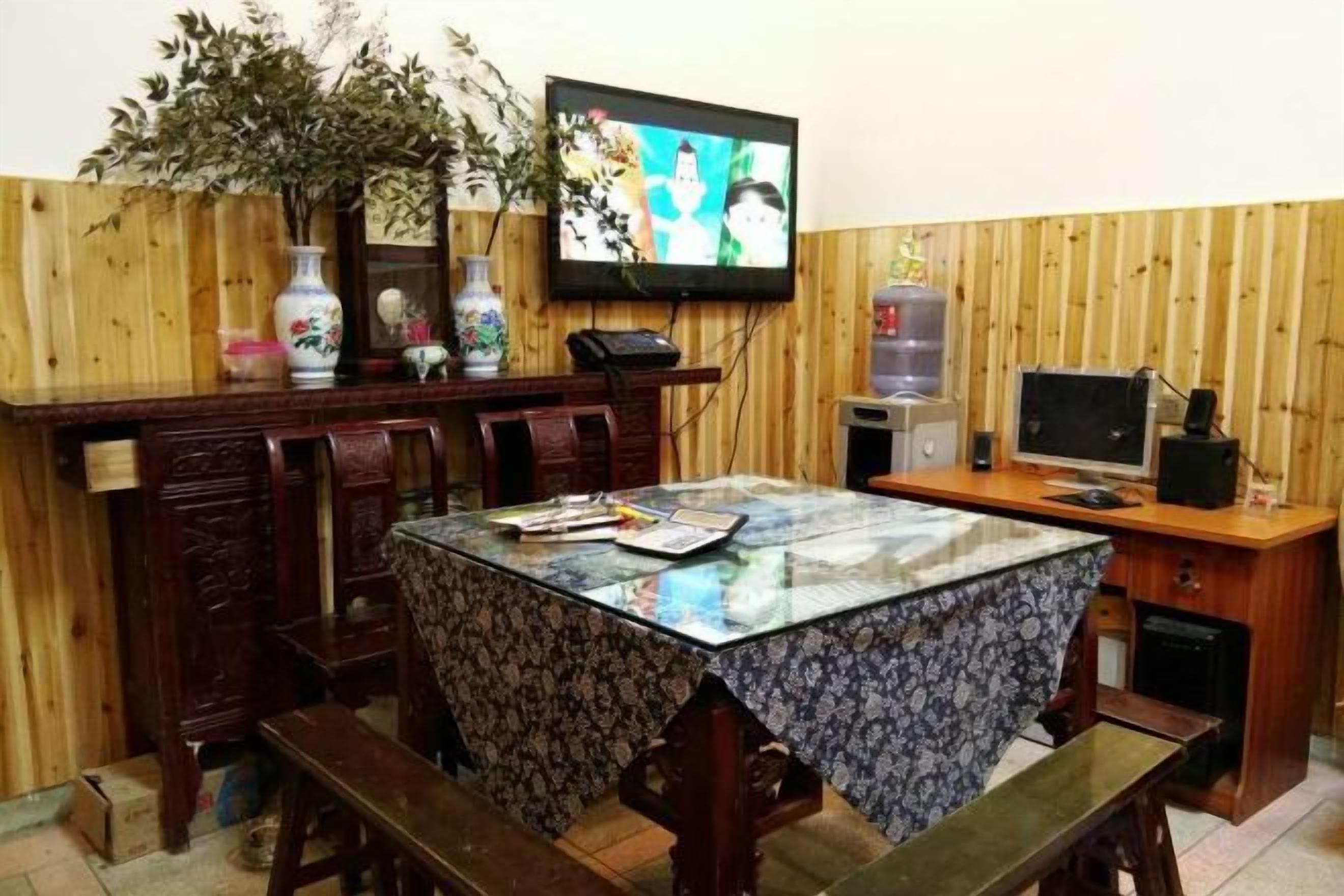 A dining area with a wooden table, benches, a television, and a water dispenser.