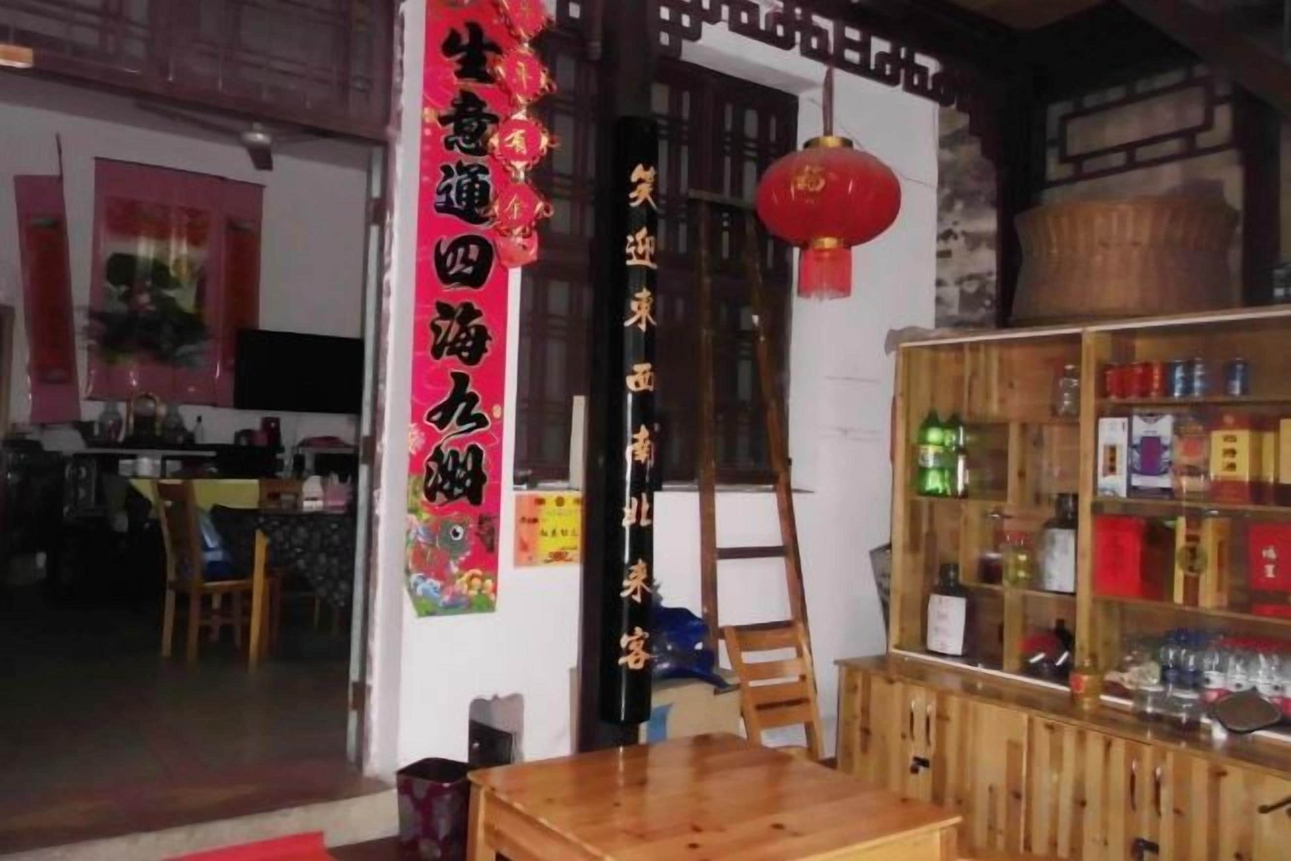 Un interior tradicional con una mesa de madera, una escalera y una estantería con botellas.