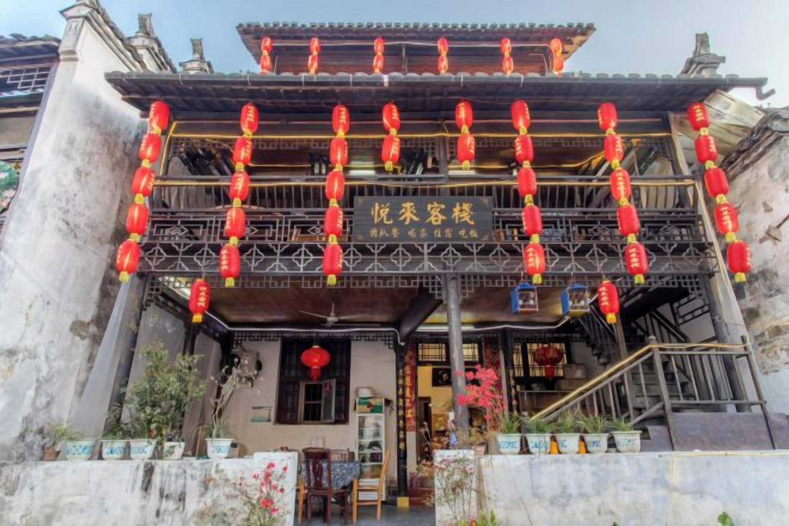A traditional building with a balcony, red lanterns, and a sign with Chinese characters.