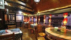 A restaurant with wooden interior, round tables, and traditional lanterns. - Likeng Yuelai Inn (Wuyuan)