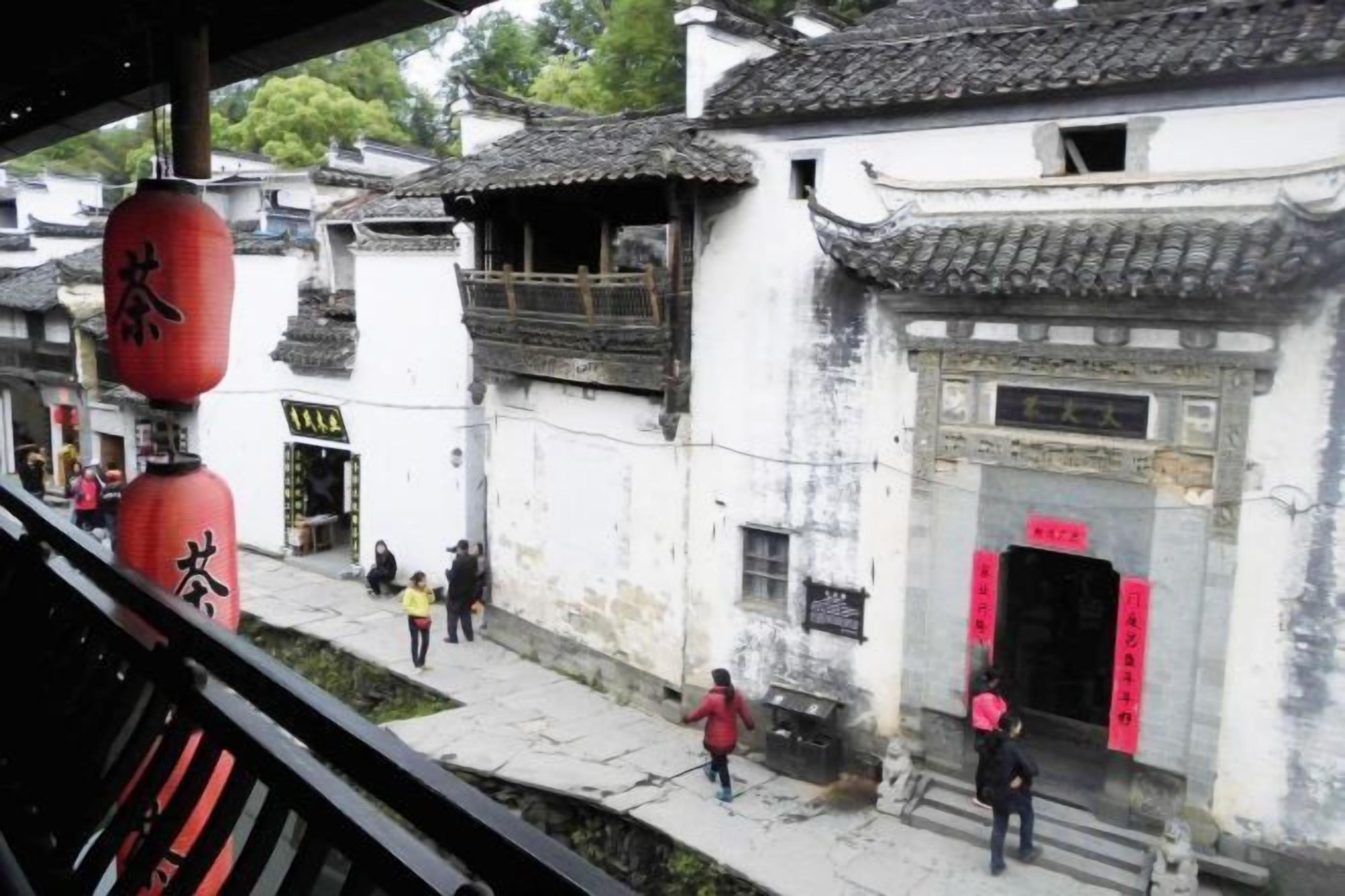 A traditional building with a tiled roof, a red lantern, and a stone entrance.