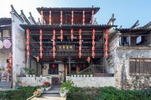Um edifício tradicional com telhado em azulejos, lanternas vermelhas penduradas e uma placa com caracteres chineses.