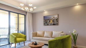 A modern living room with a sofa, two armchairs, a coffee table, and a cityscape painting on the wall. - Alba Gardens 1Bed by YourHost  (Nairobi)