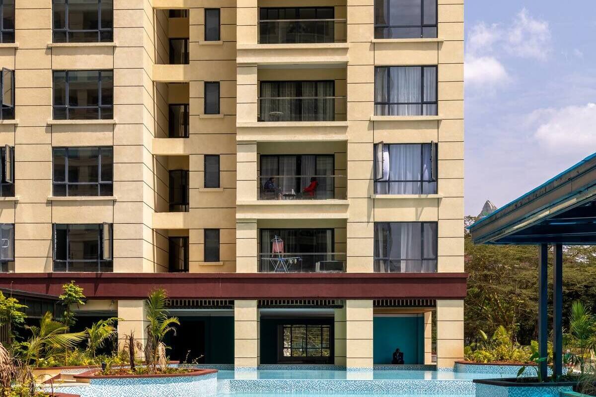 A hotel with a swimming pool, a covered outdoor area, and a building with multiple balconies.