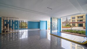 A spacious, modern hotel lobby with a blue and white color scheme, a large window offering a view of the city, and a clean, polished floor. - Alba Gardens 1Bed by YourHost  (Nairobi)