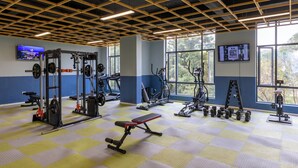 A gym with various exercise equipment, large windows, and a checkered floor. - Alba Gardens 1Bed by YourHost  (Nairobi)