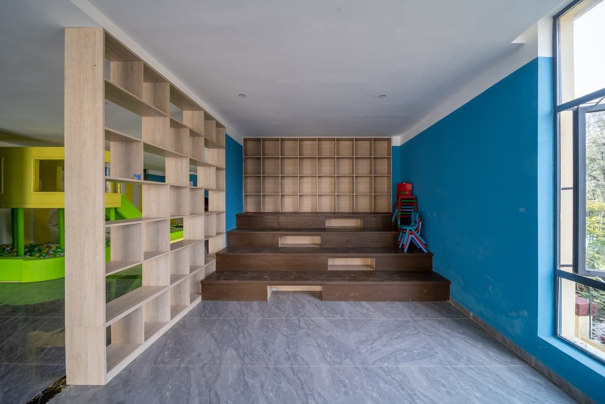 A room with a staircase, a bookshelf, and a window.