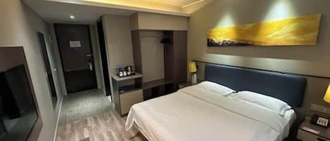 A hotel room with a large bed, a desk, a chair, a TV, and a painting on the wall.