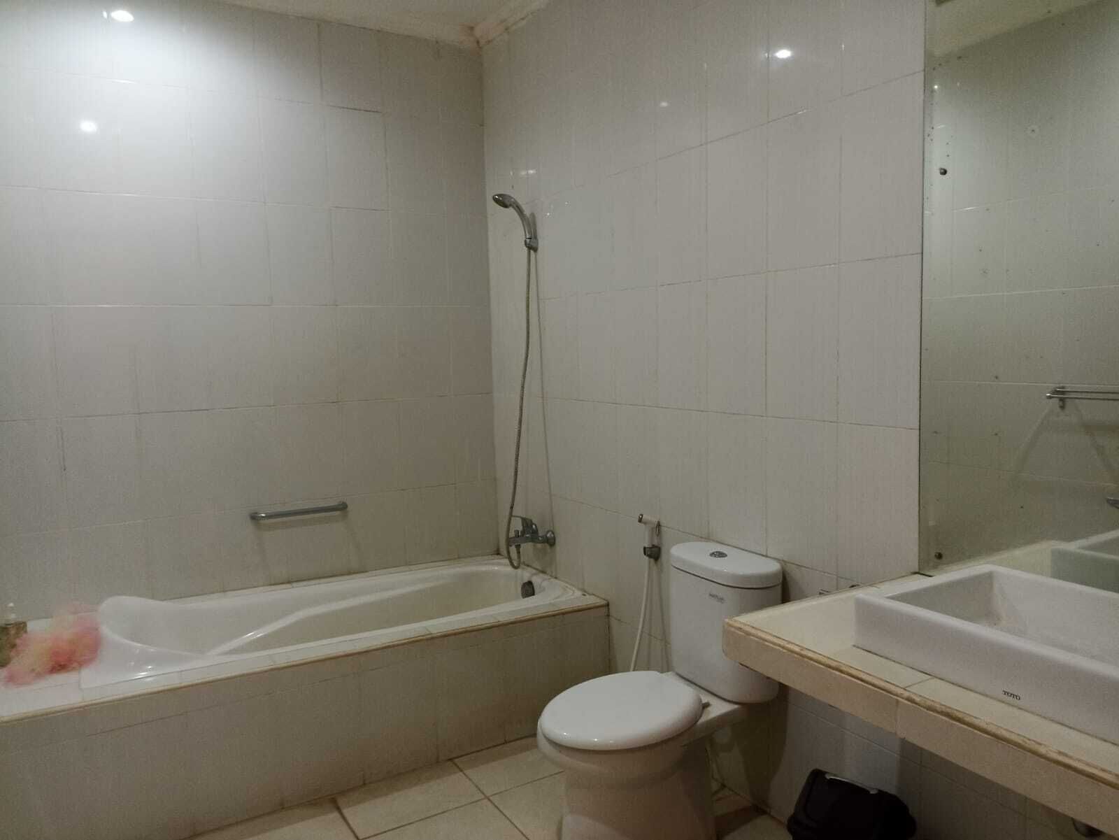 Une salle de bain comprenant une baignoire, des toilettes et un lavabo, le tout dans des tons neutres.