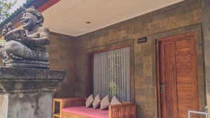Un banco de madera con cojines, una estatua de piedra y una puerta de madera.