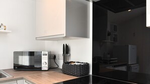 Una cocina moderna con una placa de inducción negra, un microondas y una cesta tejida negra sobre la encimera.