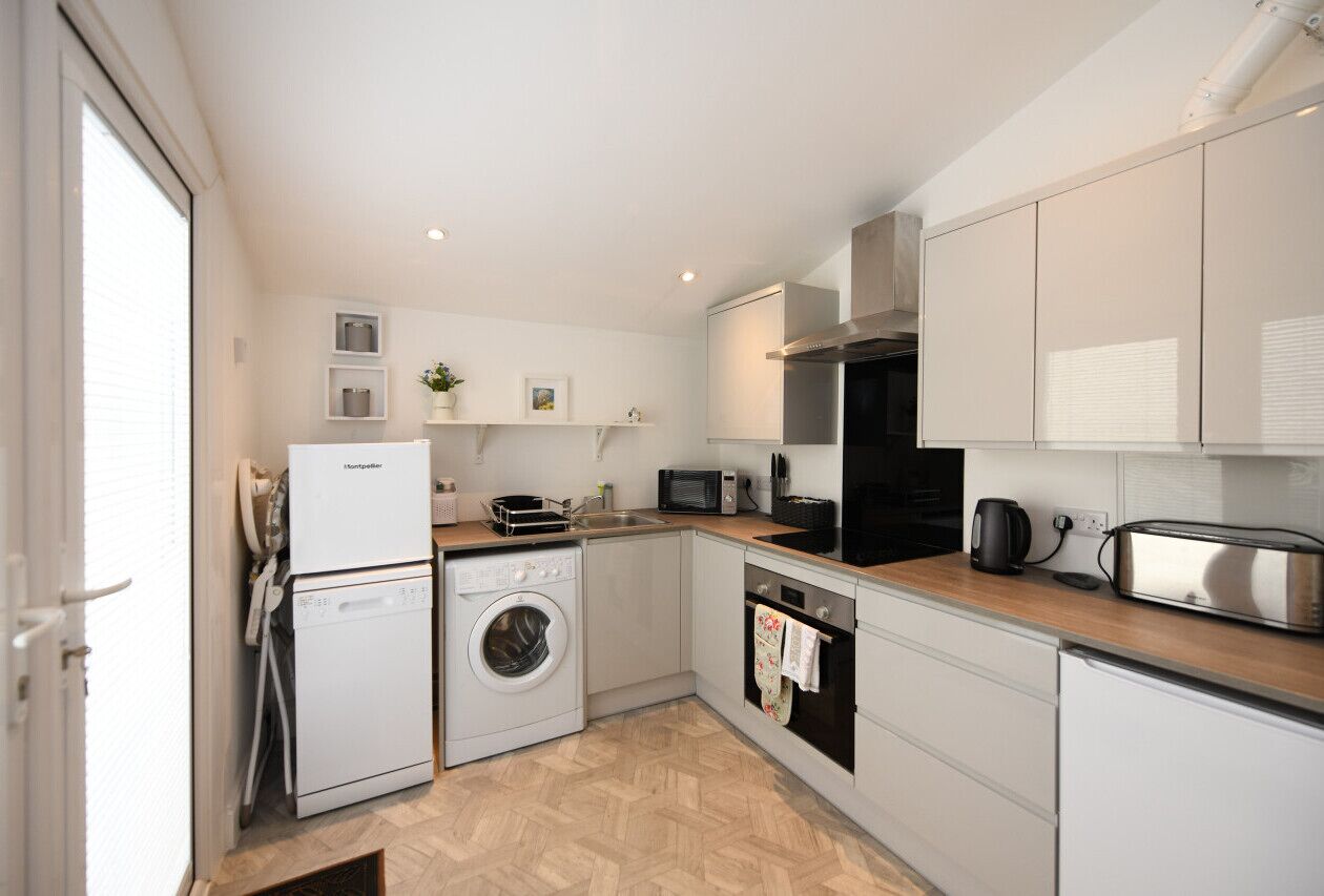 A compact kitchen with a washing machine, oven, microwave, and a toaster.